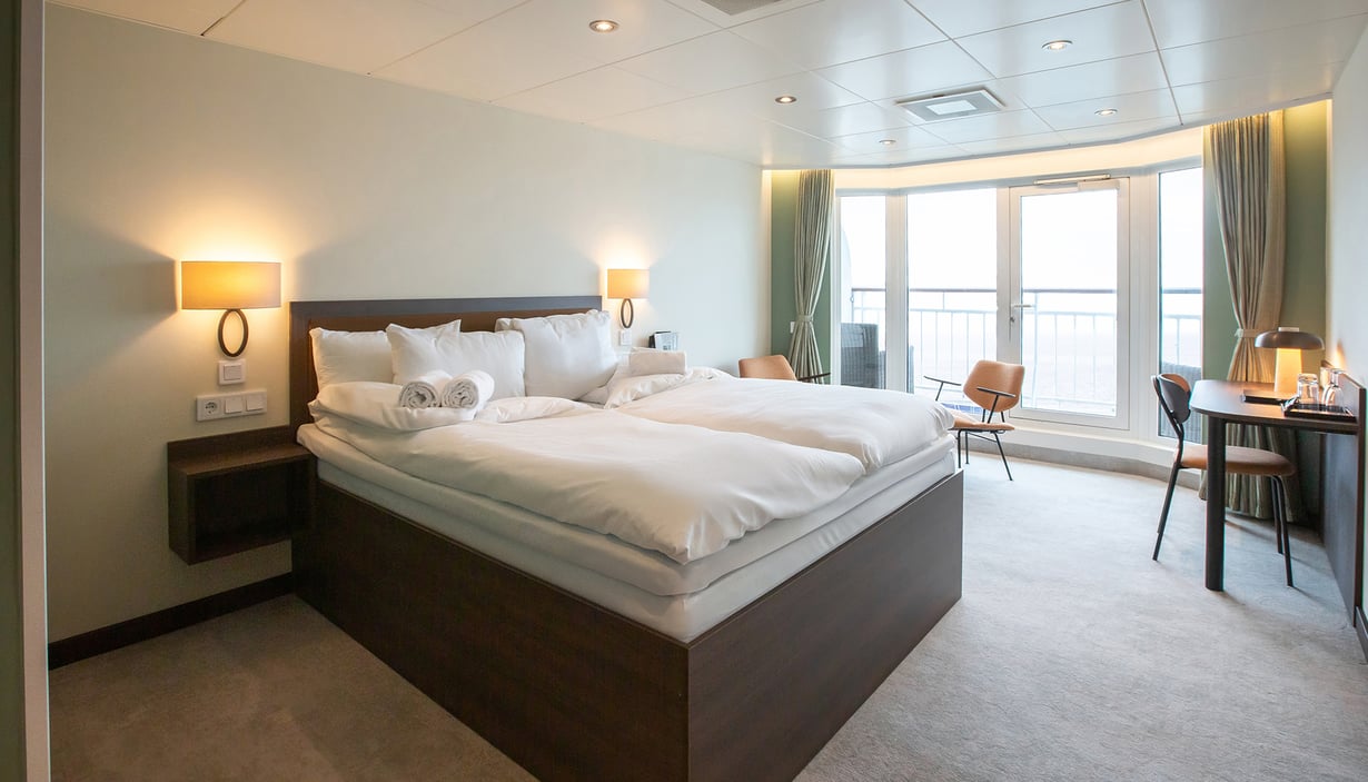 Modern cabin with a large bed, bedside tables, and a window.