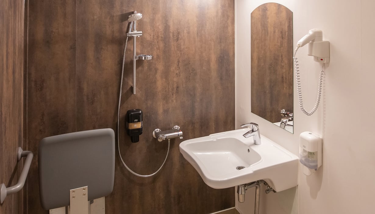 Accessible bathroom with sink, shower, and foldable seat.