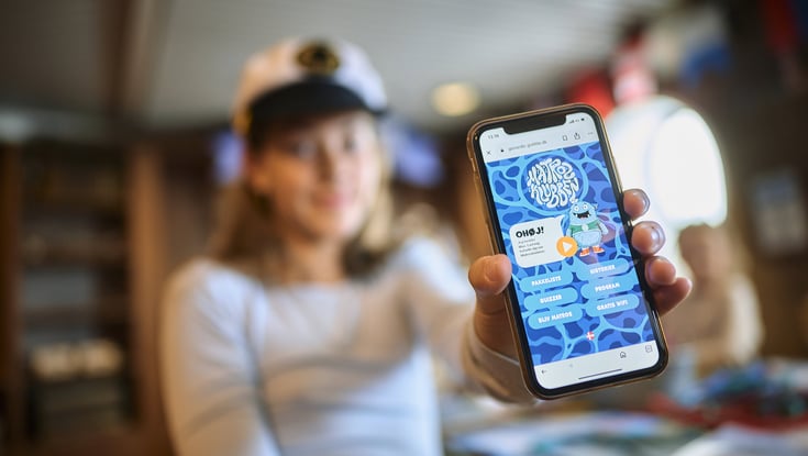 Person holding a smartphone displaying an application or website related to the Matrosklubben.