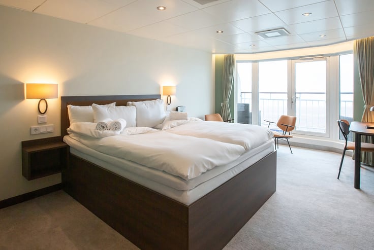 Modern cabin with a large bed, bedside tables, and a window.